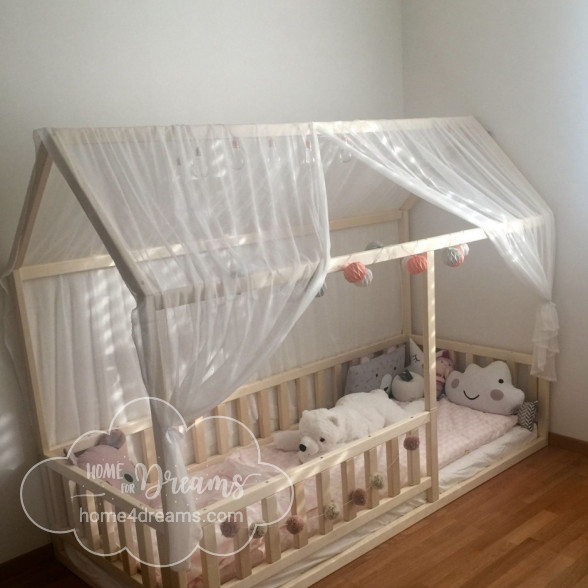 A children’s floor bed with soft toys and a bed canopy