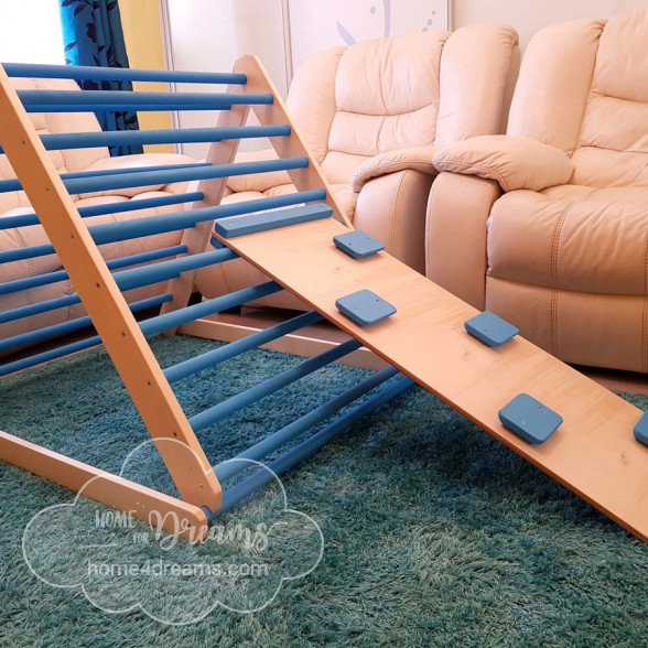 A baby climbing toy triangle with a climbing board placed inside of a living room