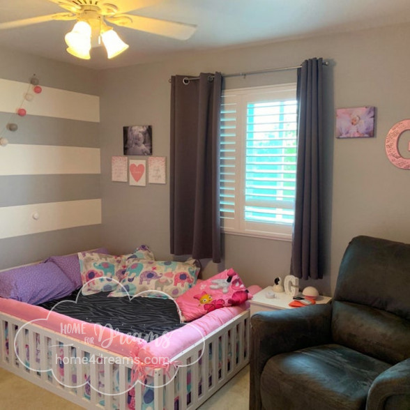 A natural wood toddler bed with pillows and bedding