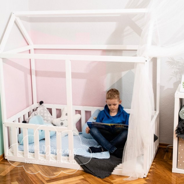 A boy sitting in a floor bed with rails