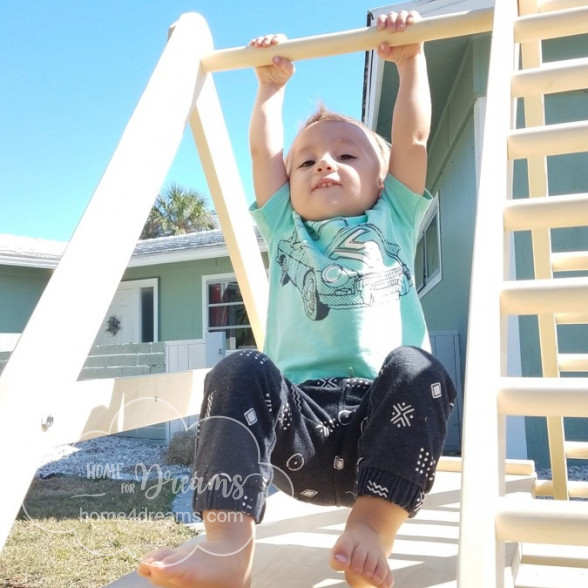 A child hanging on a climbing ladder for toddlers