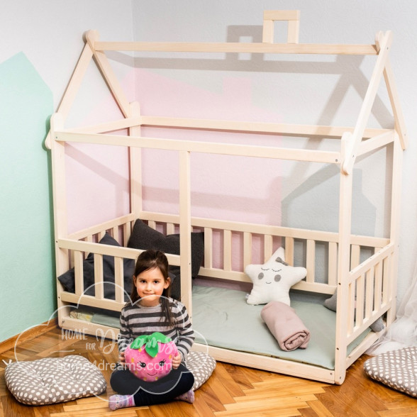 A girl sitting next to a Montessori floor bed