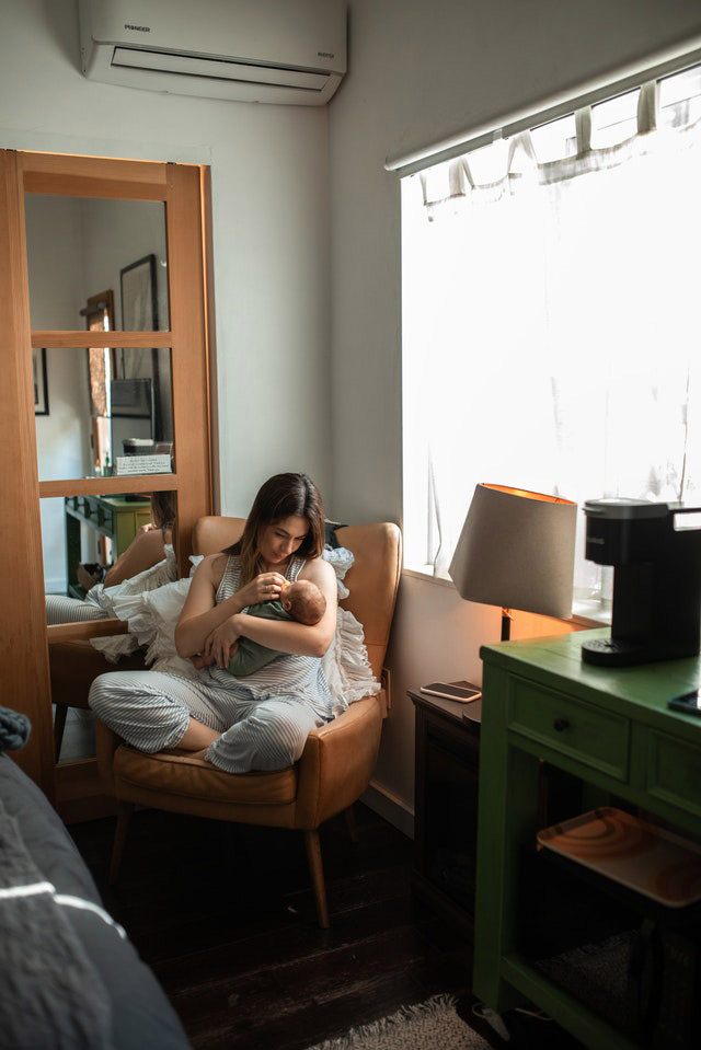 A woman sitting a chair and holding a baby